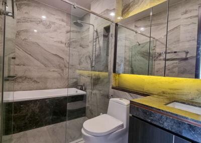 Modern bathroom interior with marble tiles, glass shower enclosure, and bathtub