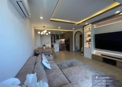 Modern living room interior with open kitchen design, comfortable sofa, and entertainment unit