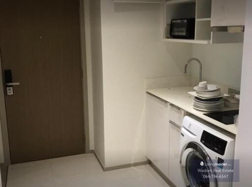 Compact modern kitchen area with washing machine and white cabinetry