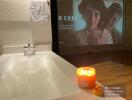 Cozy bathtub with a lit candle and entertainment screen in modern bathroom
