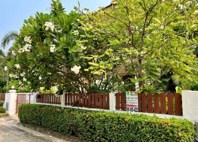 Lush green front yard with private fencing and a visible for-sale sign