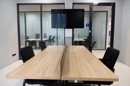 Modern office meeting room with large wooden table and ergonomic chairs