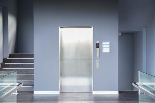 Modern elevator in a sleek building lobby with staircase