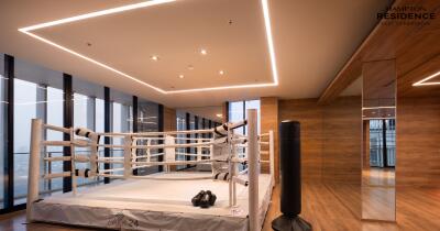 Modern indoor gym space in a luxury residence featuring a boxing ring, punching bags, and elegant wooden floors