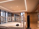 Modern indoor gym space in a luxury residence featuring a boxing ring, punching bags, and elegant wooden floors