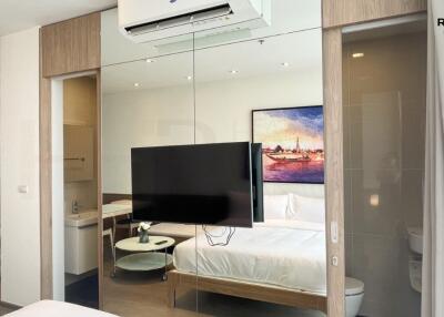 Modern studio apartment bedroom with integrated living space features large TV and kitchenette