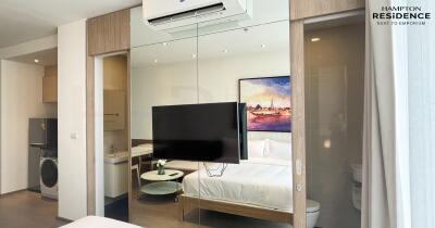 Modern studio apartment bedroom with integrated living space features large TV and kitchenette