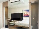 Modern studio apartment bedroom with integrated living space features large TV and kitchenette