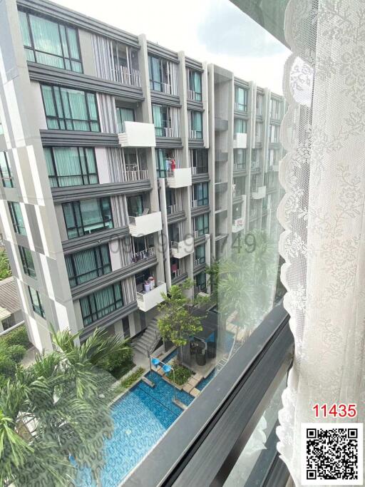 View from apartment window showing external apartment buildings and swimming pool