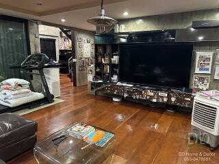 Spacious living room with modern decor, featuring a large TV, treadmill, and various decorations