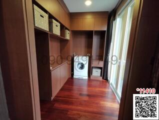 Spacious storage room with built-in wooden cabinets and washing machine