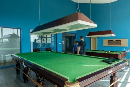 Spacious game room with a large billiard table and striking blue walls