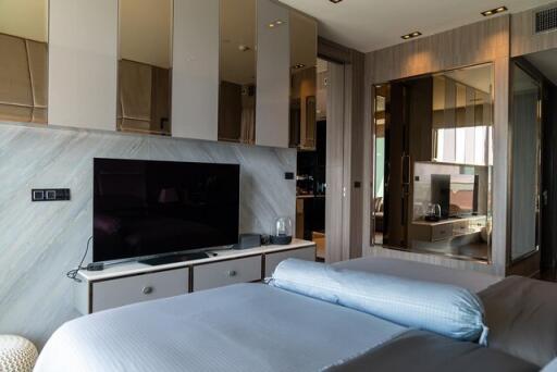 Modern bedroom with integrated entertainment unit and reflective wardrobe doors