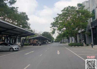 Spacious street view within a residential area featuring covered parking and modern townhouses