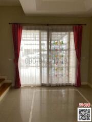 Elegant and bright living room with large window dressed in maroon and white curtains