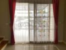 Elegant and bright living room with large window dressed in maroon and white curtains