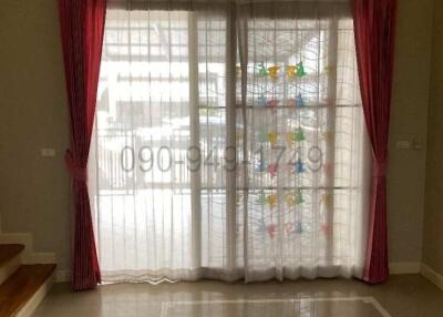 Elegant and bright living room with large window dressed in maroon and white curtains