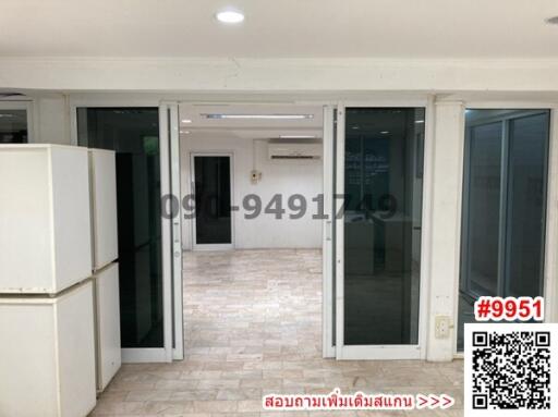 Spacious building interior with multiple glass doors and white tiled flooring