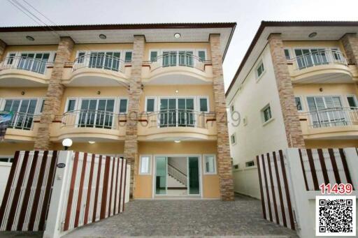 Exterior view of a modern multi-story residential building with balconies and gated entrance