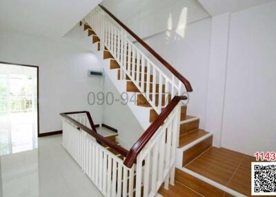 Spacious and bright staircase with wooden steps and white railing in a modern home