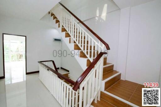 Spacious and bright staircase with wooden steps and white railing in a modern home