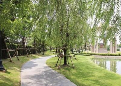 Lush green park with walking path and pond in a residential area