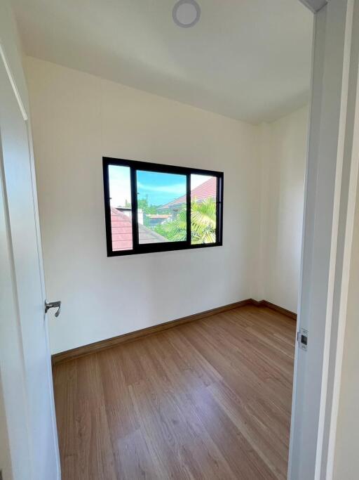 Bright and empty bedroom with large window and wooden floor