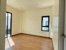 Spacious and well-lit bedroom with hardwood flooring and balcony access