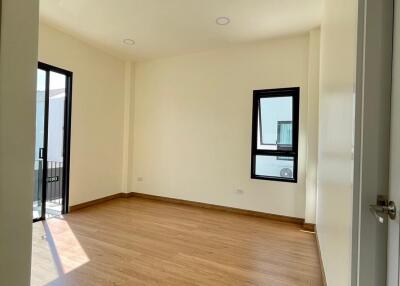 Spacious and well-lit bedroom with hardwood flooring and balcony access