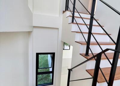 Modern staircase with wooden steps and black metal railing in a bright home