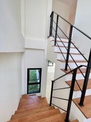 Modern staircase with wooden steps and black metal railing in a bright home