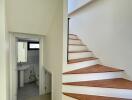 Brightly lit staircase with wooden steps leading to an upper floor and a view into a modern bathroom