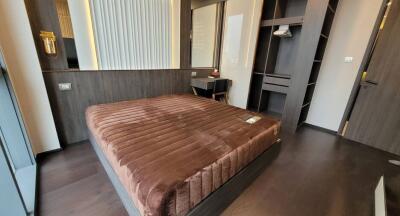 Modern bedroom in a real estate property with dark wood flooring and a plush brown bed