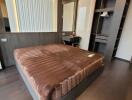 Modern bedroom in a real estate property with dark wood flooring and a plush brown bed