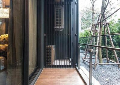 Modern balcony with glass walls and metal railings looking out to a garden