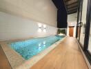 Elegant outdoor swimming pool area with wooden deck and modern lighting at night