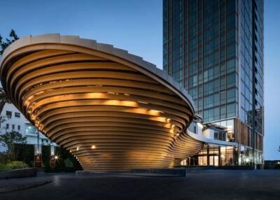 Modern architectural building with unique curved design and illuminated facade at twilight