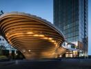 Modern architectural building with unique curved design and illuminated facade at twilight