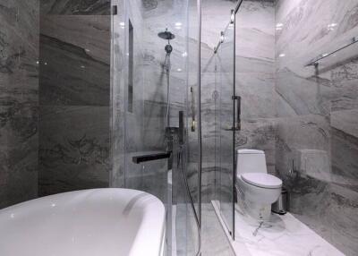 Modern bathroom with marble finishes featuring a freestanding bathtub and glass shower