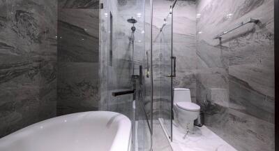 Modern bathroom with marble finishes featuring a freestanding bathtub and glass shower