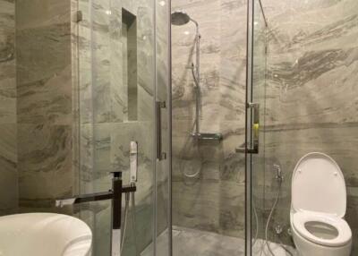 Modern bathroom with marble walls, glass shower, and white fixtures