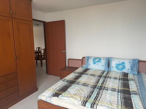 Spacious bedroom with large bed, wooden wardrobe, and access to another room