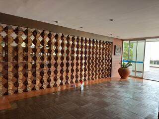 Spacious lobby area with decorative wooden wall and large planter