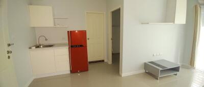 Compact studio apartment with integrated kitchen, modern red fridge, and minimalist living area