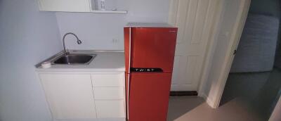 Compact kitchen with modern red refrigerator and white cabinetry