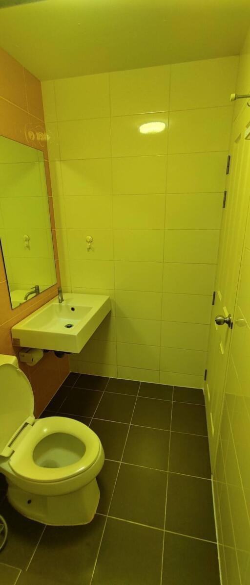 Compact bathroom with yellow wall tiles and modern amenities