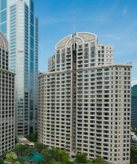 High-rise residential building surrounded by greenery and modern skyscrapers