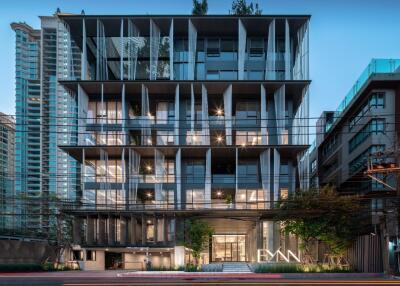 Modern multi-story residential building at dusk with illuminated interiors and a vibrant facade