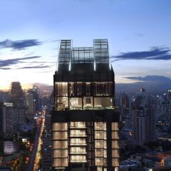 Modern high-rise building exterior at twilight with illuminated interiors and cityscape background