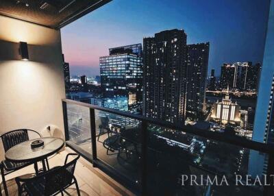 City view from high-rise apartment balcony at dusk with outdoor seating